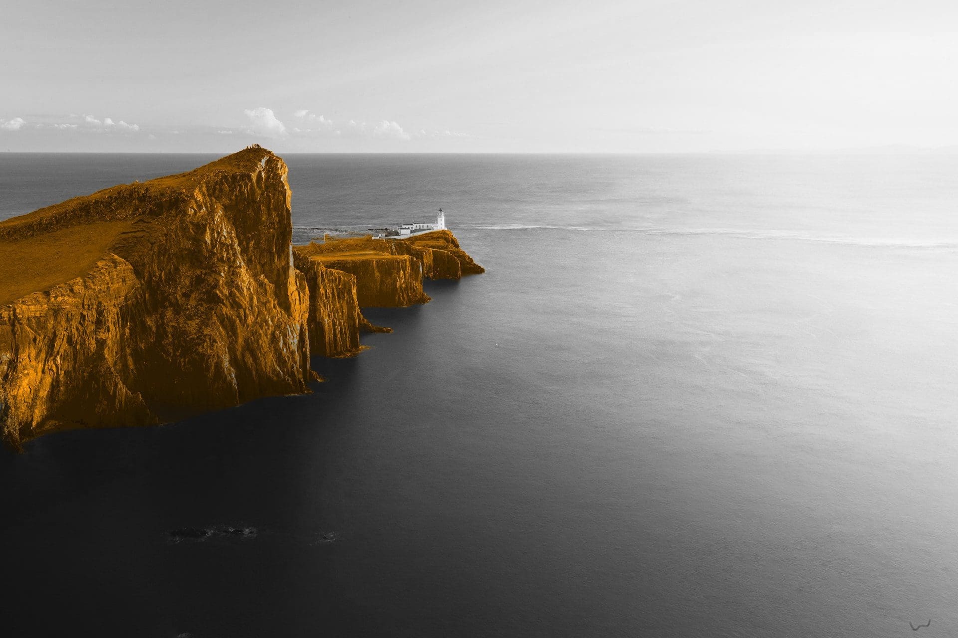 A black and white image of an ocean, with a orange hill in the middle