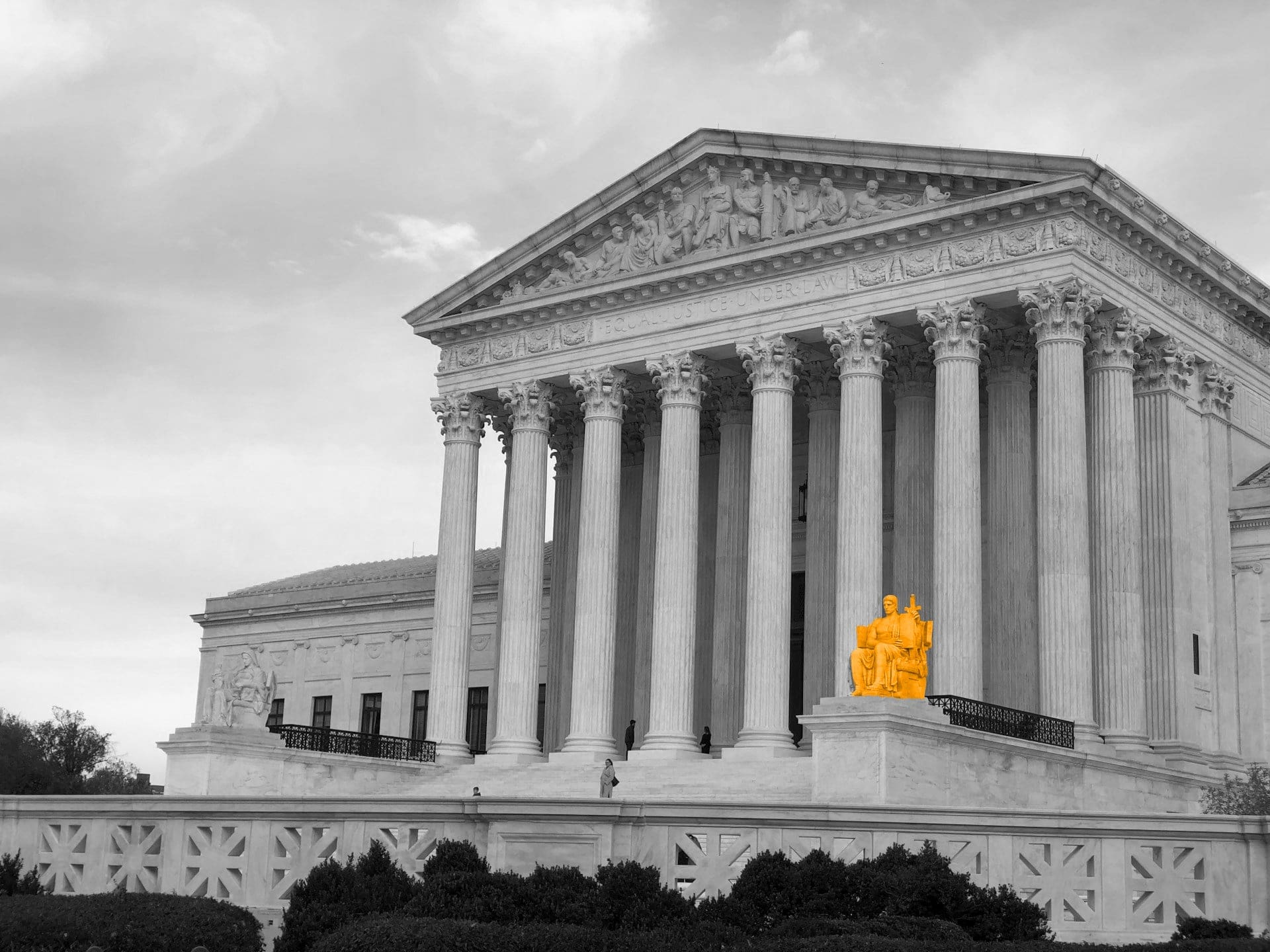 A black and white image of a building with pillars, with a orange statue of a man