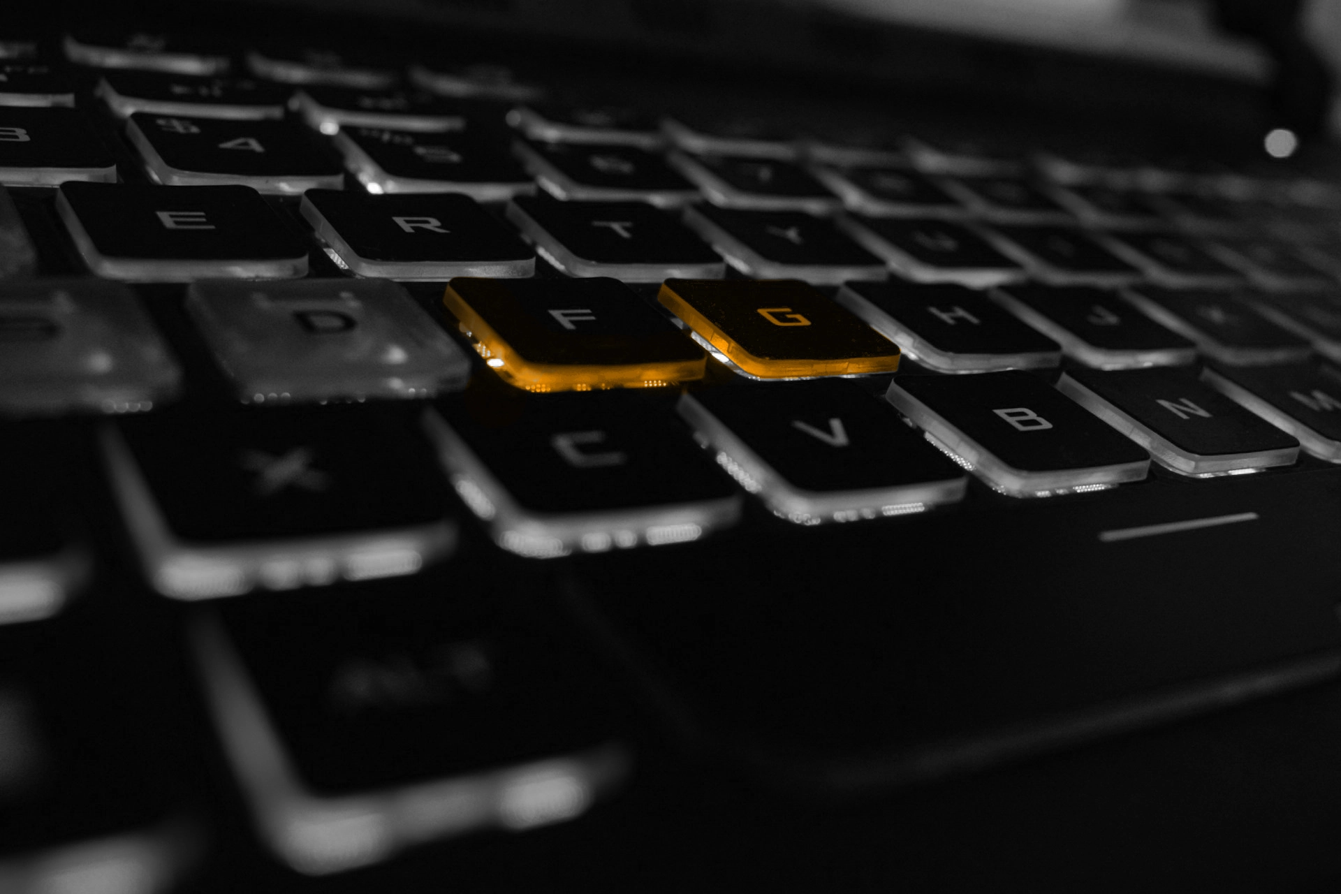 A black and white image of a laptops keyboard, with the F and G keys being orange