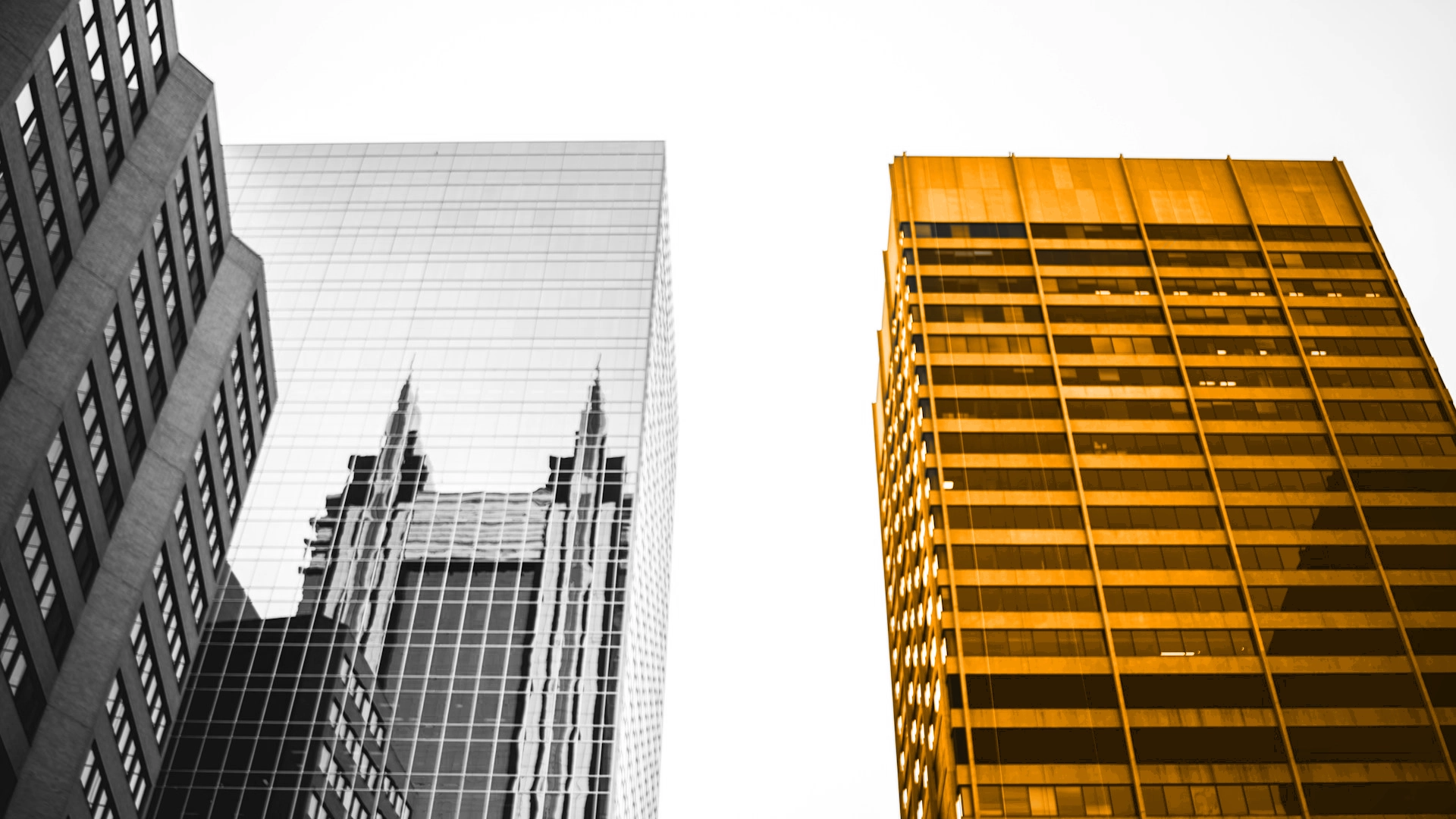 A black and white image of three buildings, one of which being orange