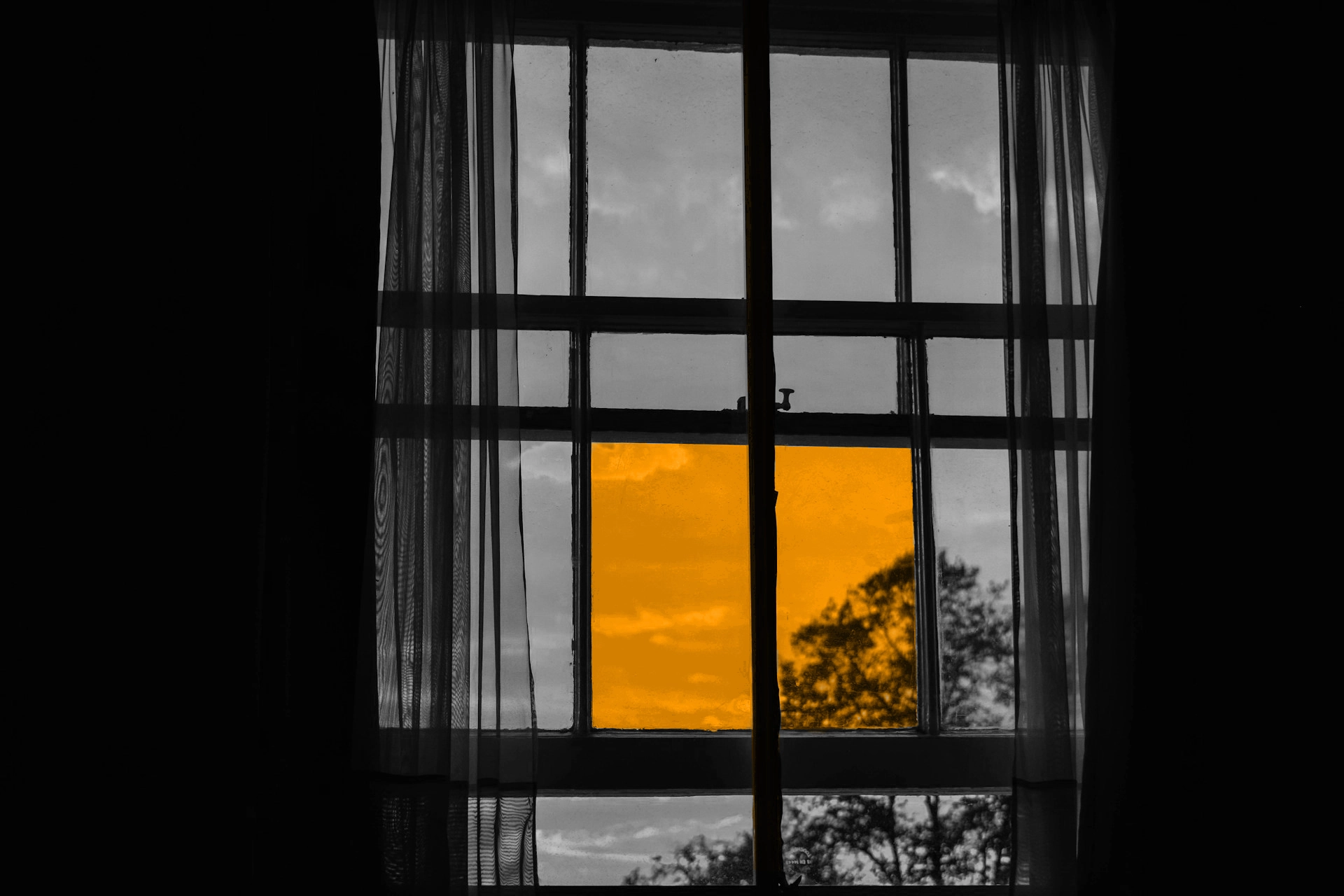 A black and white image of a window, but two of the window panes are orange