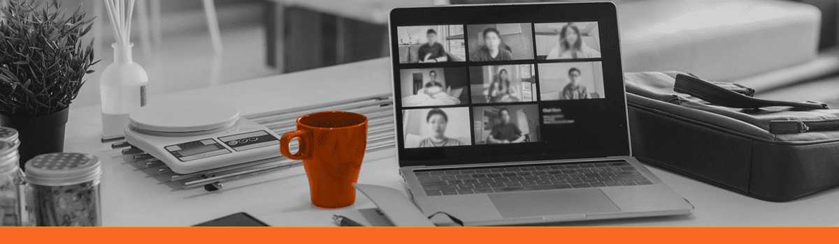 A black and white image of a laptop, with a orange mug next to it